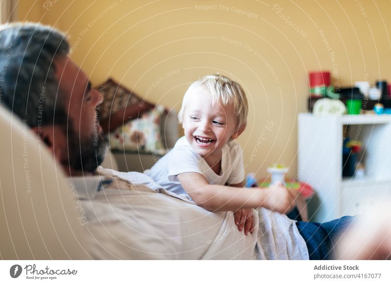 Father playing with son in living room man cuddle father home having fun cheerful positive bonding entertain kid happy blond enjoy childhood playful leisure boy