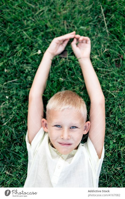 Happy boy resting on lawn in daylight kid happy child grass chill weekend pleasure hand behind head relax cheerful blond childhood carefree summer delight