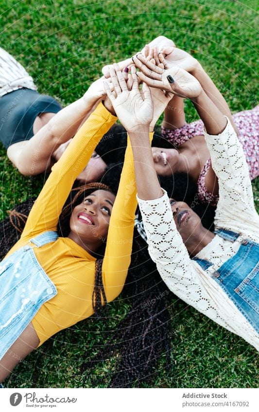 Carefree diverse women stacking hands together stack hands friendship unity company lying grass carefree multiethnic multiracial black african american park