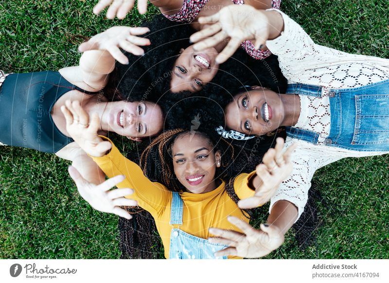 Carefree diverse women stacking hands together stack hands friendship unity company lying grass carefree multiethnic multiracial black african american park