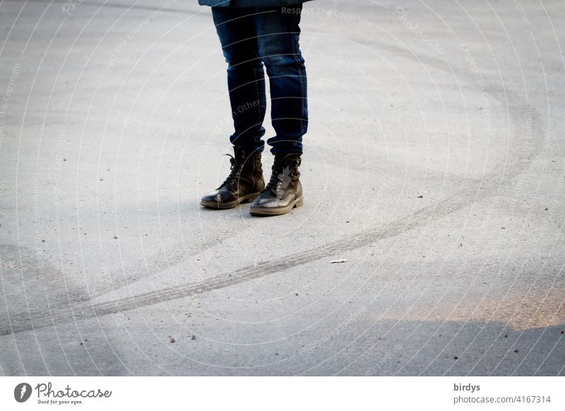 female person with jumper boots stands on an empty place surrounded by tire tracks of a drifting car Woman Legs Combat boots Asphalt Skid marks Dynamics