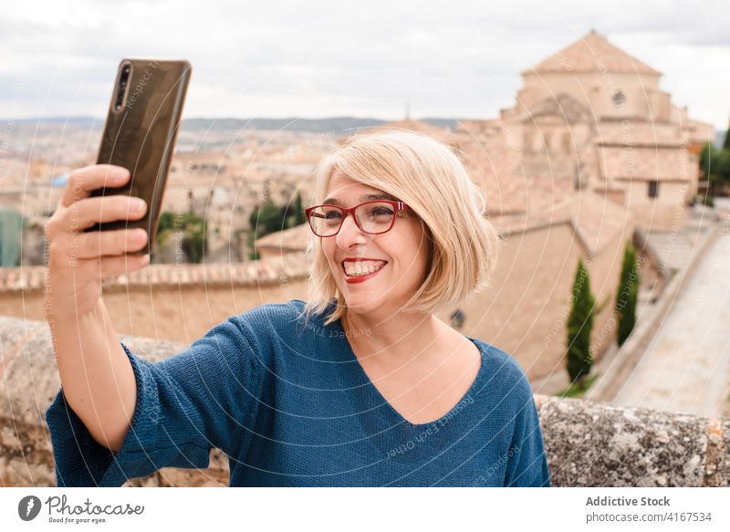 Happy traveling woman taking selfie against medieval buildings town architecture historic sightseeing traveler smartphone female cuenca spain visit mobile