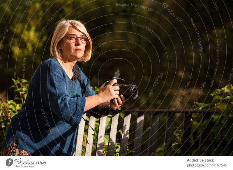 Female photographer with camera shooting nature woman forest fence take photo photo camera capture environment photography hobby artist creative work female