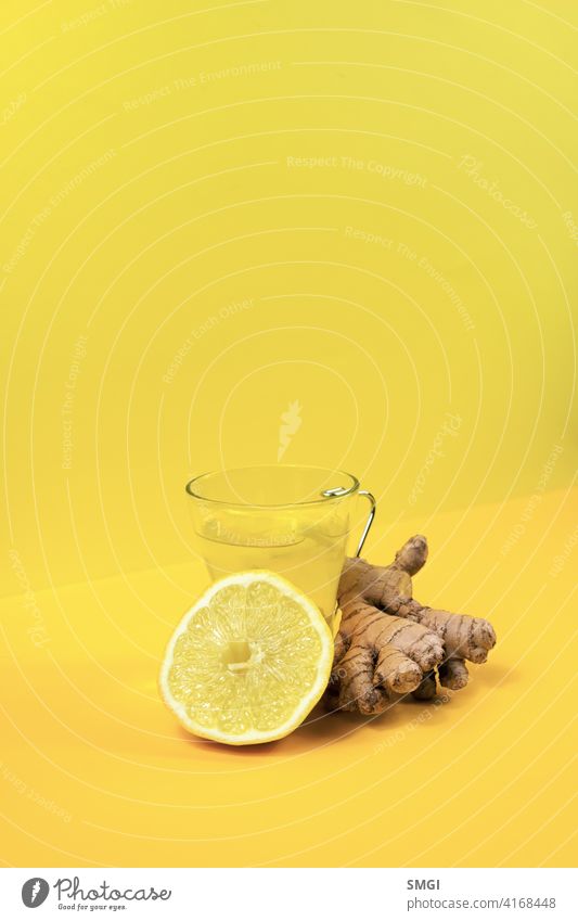 Glass cup with ginger and lemon tea, on a yellow background along with its ingredients. drink medicine healthy root herbal hot rustic vitamin relaxation liquid