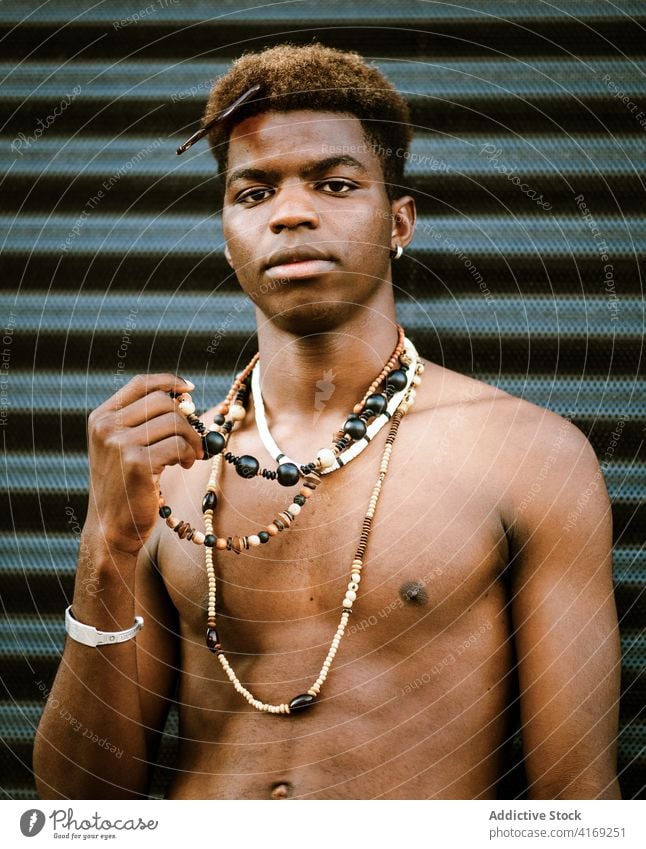 Serious black man in trendy jewelry in street necklace golden young luxury serious modern urban male ethnic african american fashion various naked torso