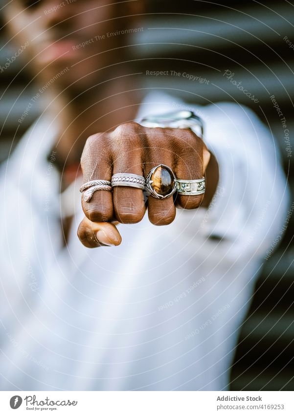 Unrecognizable ethnic man showing fist with fingers at camera ring silver style hand accessory jewelry trendy cool male black african american fashion
