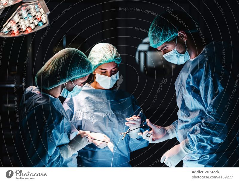 Team of medics doing surgery in hospital surgeon operating theater team together group thread tool assistant stitch nurse operation instrument work skill job