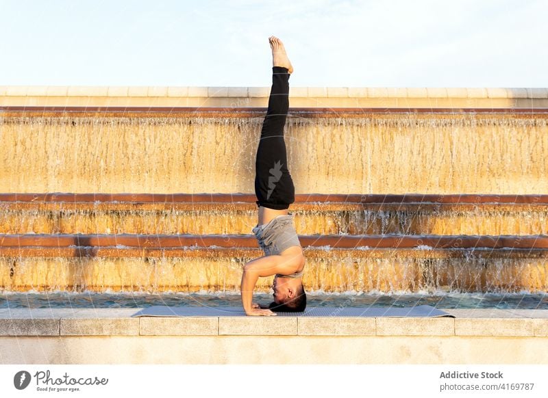 Man performing headstand and doing yoga pose man supported headstand pose asana balance mental zen meditate male mat fountain city healthy sunny vitality