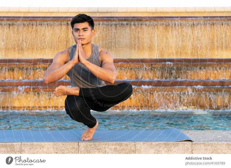Flexible man practicing yoga in Toe Stand pose toe stand pose balance flexible city stress relief asian mindfulness mental tranquil ethnic male asana