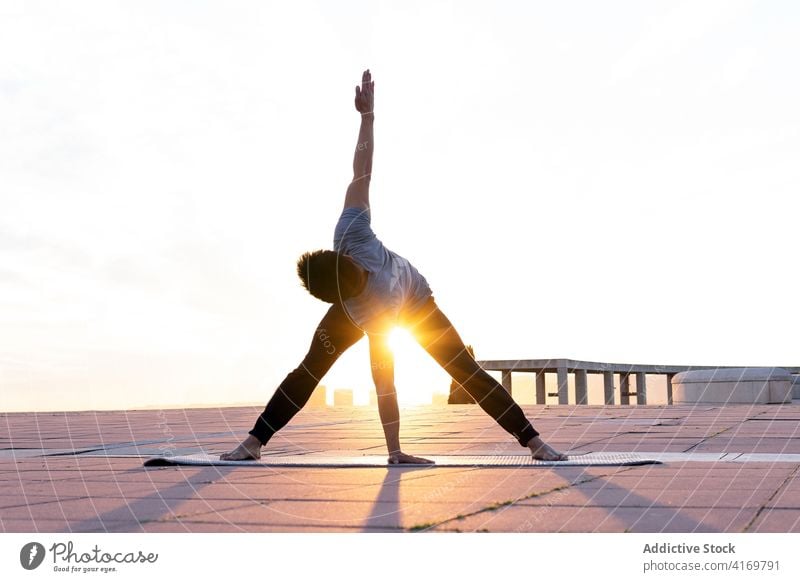 Flexible man practicing yoga in Revolved Wide Legged Forward Bend pose flexible forward bend asana revolved wide legged forward bend pose balance sunset stretch