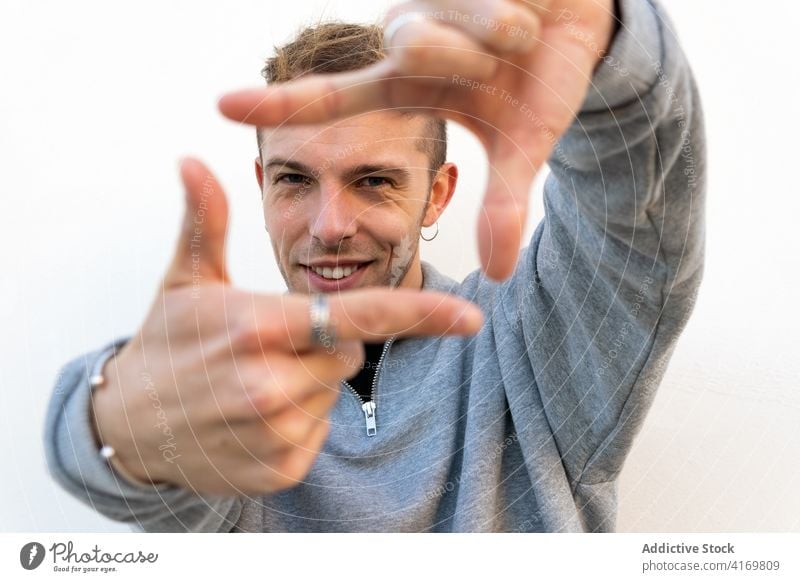 Cheerful man making frame with hands finger photography hipster cheerful smile gesture focus young happy male positive optimist creative shoot capture friendly