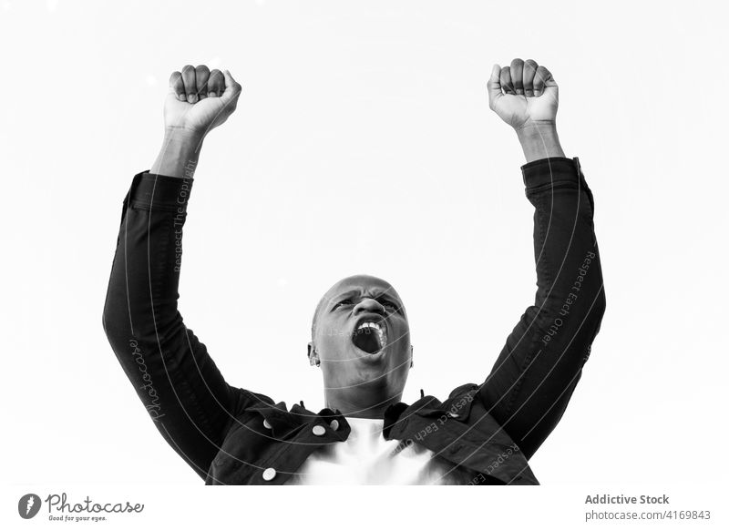 Black man celebrating success with raised arms celebrate fist up achieve winner triumph shout scream male black ethnic african american victory joy gesture goal