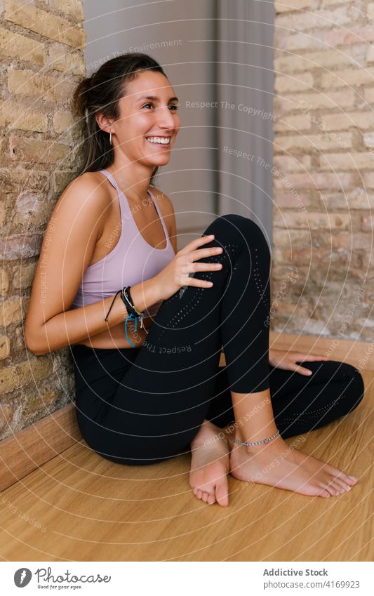 Young woman resting in yoga studio break smile lesson brick wall floor sportswear female young slim fit wellness healthy barefoot cheerful relax wellbeing joy