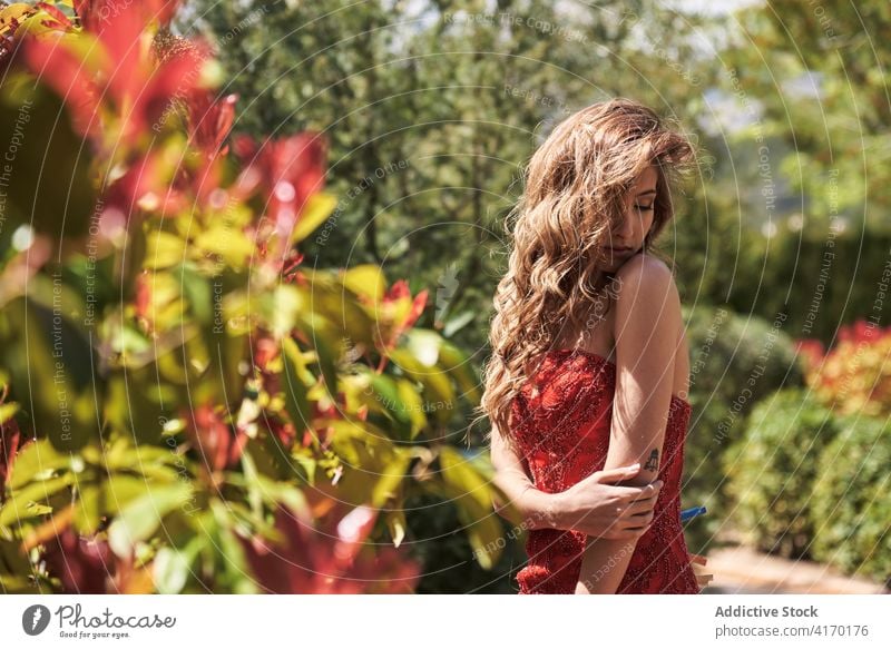 Graceful woman in red dress in lush garden grace elegant dreamy tender summer young nature style long hair romantic idyllic tranquil enjoy sunlight lady