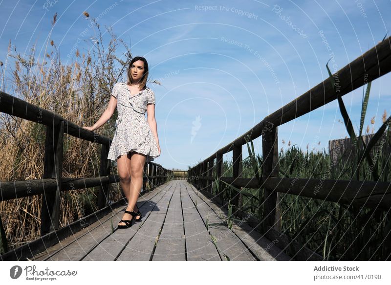 Woman standing on wooden bridge over lake woman boardwalk pier alone summer nature river water rest calm vacation tranquil countryside serene female lifestyle