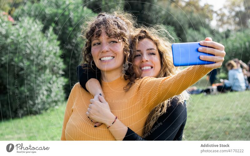Cheerful friends taking selfie in park women together friendship cheerful having fun friendly smartphone charming sunny weekend gadget device happy casual