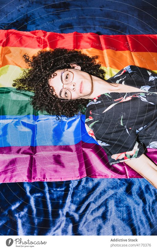 Relaxed female lying on LGBT flag on bed woman equal rainbow homosexual respect tolerance upside down right community gender solidarity same sex discriminate