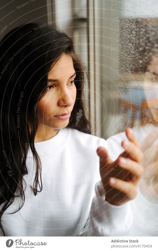 Peaceful woman touching window with waterdrops raindrop melancholy mood droplet peaceful tranquil ethnic female tender calm solitude lonely alone gentle