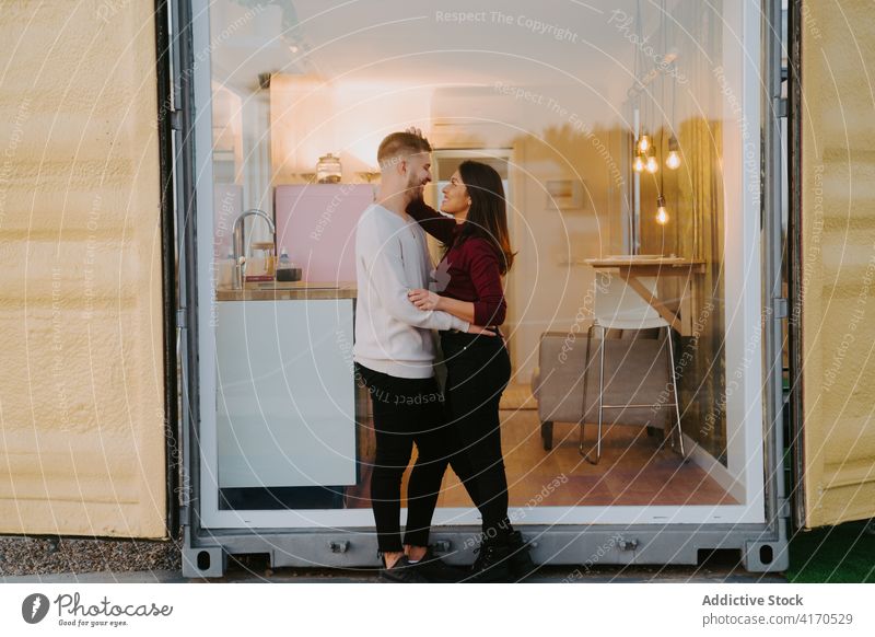 Couple standing near window of container house modern couple compact countryside building construction dwell cuddle together love relationship glass