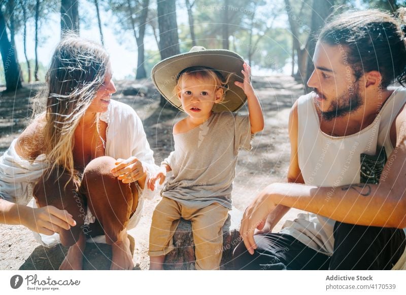 Family spending weekend together in forest barefoot hippie family couple relax kid hat cute multiethnic multiracial diverse woods parent sunny nature child