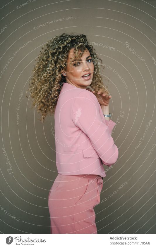 Fashionable woman in trendy outfit in studio apparel style curly hair afro hairstyle model female slim individuality contemporary cool cloth elegant jacket suit
