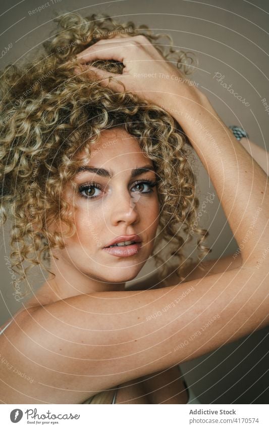 Serene woman with curly hair in studio afro hairstyle charming appearance touch hair makeup perfect serene female trendy fashion model beauty vogue feminine