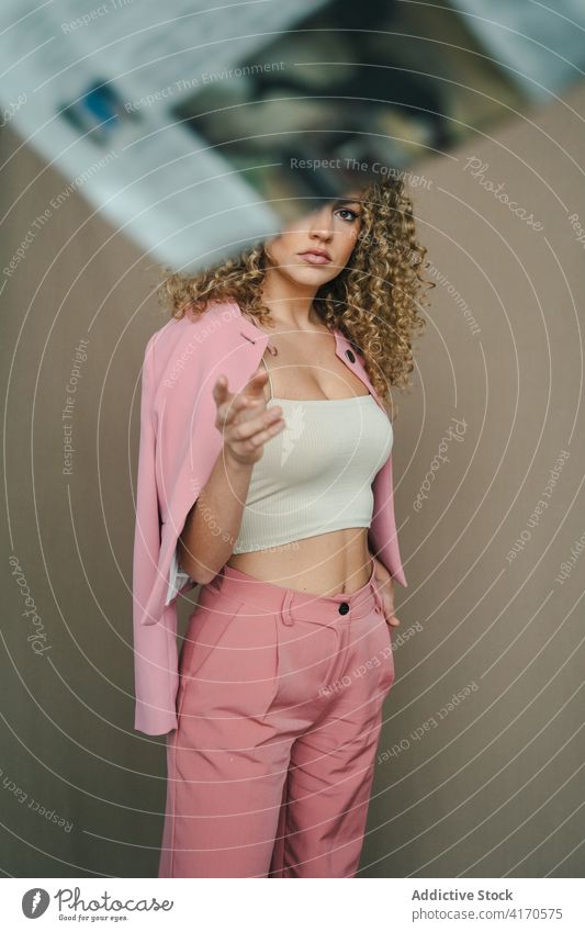 Thoughtful woman in stylish outfit in studio pensive suit costume pink afro hairstyle trendy female long hair modern stand serious think gorgeous charming
