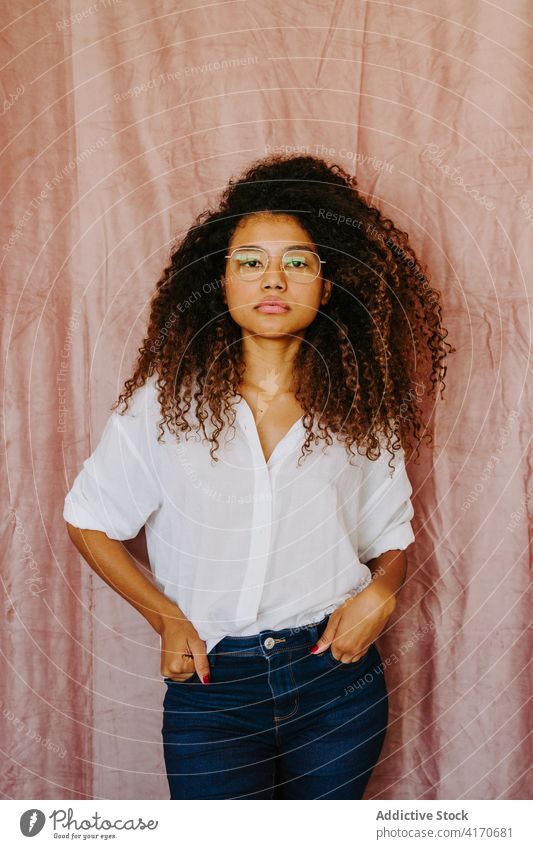 Black woman looking at camera afro hairstyle charming youth casual female ethnic black african american outfit curly hair joy glasses optimist fashion cool