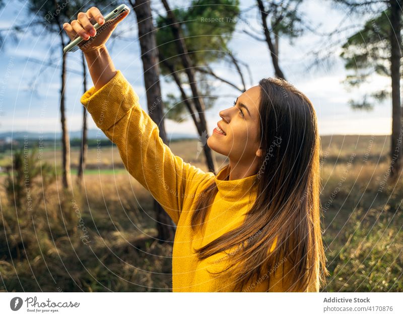 Smiling woman taking selfie in meadow in fall autumn relax smartphone self portrait charming weekend enjoy female sweater yellow dry field device gadget nature