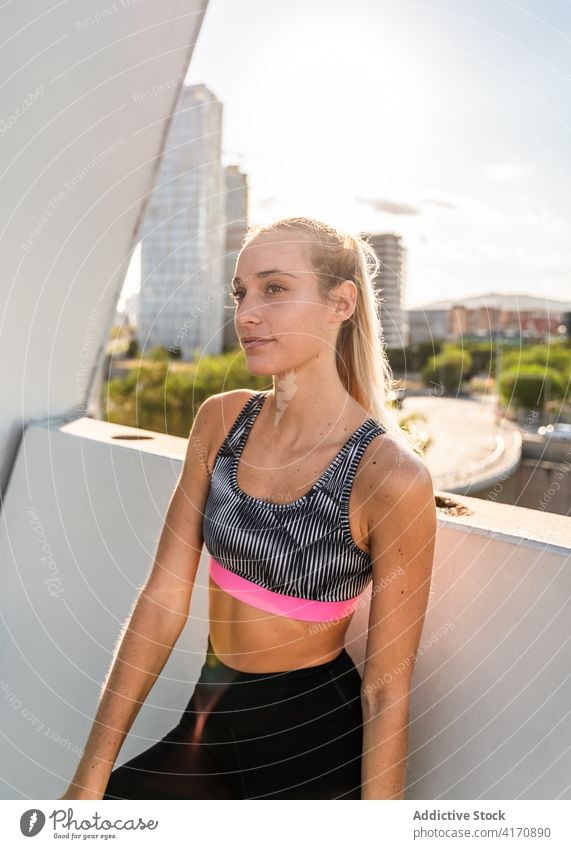 Slim woman in sportswear resting after workout on terrace fitness sporty urban activewear training recreation young female city athlete wellness lifestyle slim