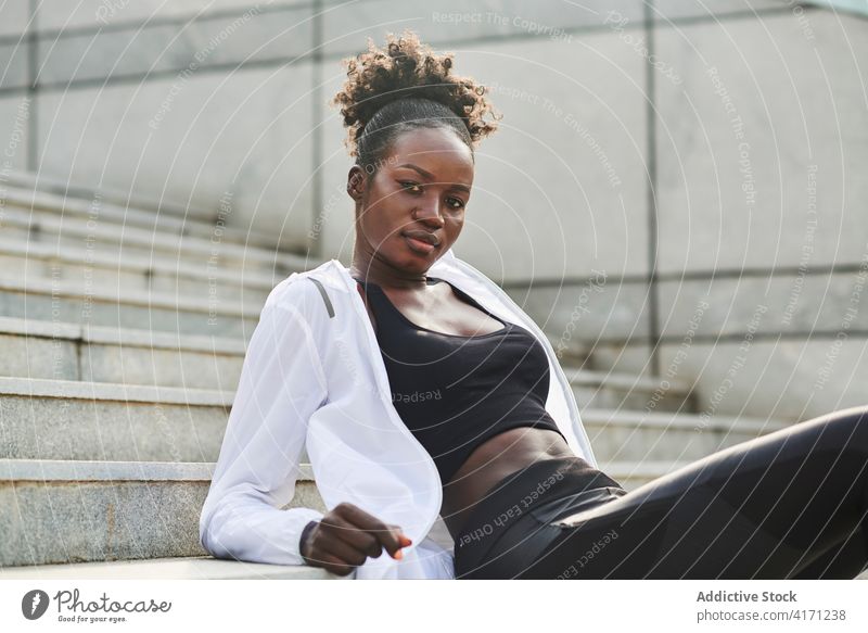 Black sportswoman relaxing on stairs in city workout break athlete confident sportswear runner female ethnic black african american stone street rest sit