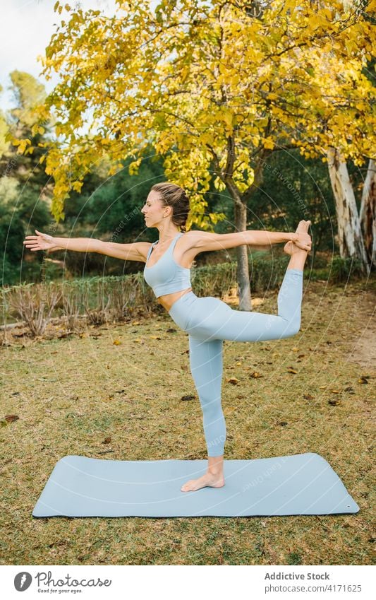 Woman standing in Lord of the Dance yoga pose in park woman lord of the dance natarajasana balance stretch practice female wellness lifestyle harmony wellbeing