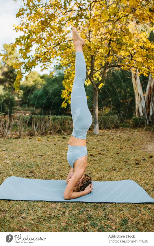 Woman in Supported Headstand pose doing yoga in park headstand supported headstand woman balance salamba sirsasana mat stress relief recovery female wellbeing