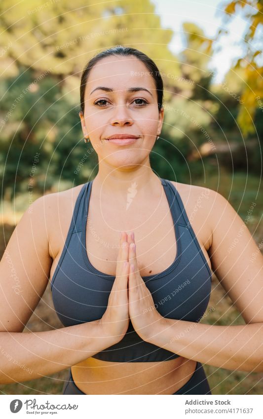 Smiling woman doing yoga in park namaste gesture practice mindfulness prayer hand content female zen calm energy harmony peaceful nature vitality healthy relax