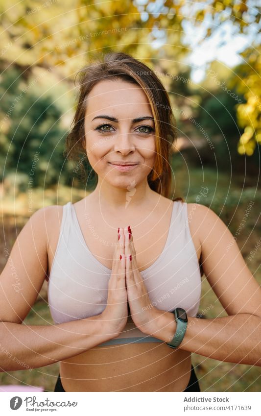 Smiling woman doing yoga in park namaste gesture practice mindfulness prayer hand content female zen calm energy harmony peaceful nature vitality healthy relax