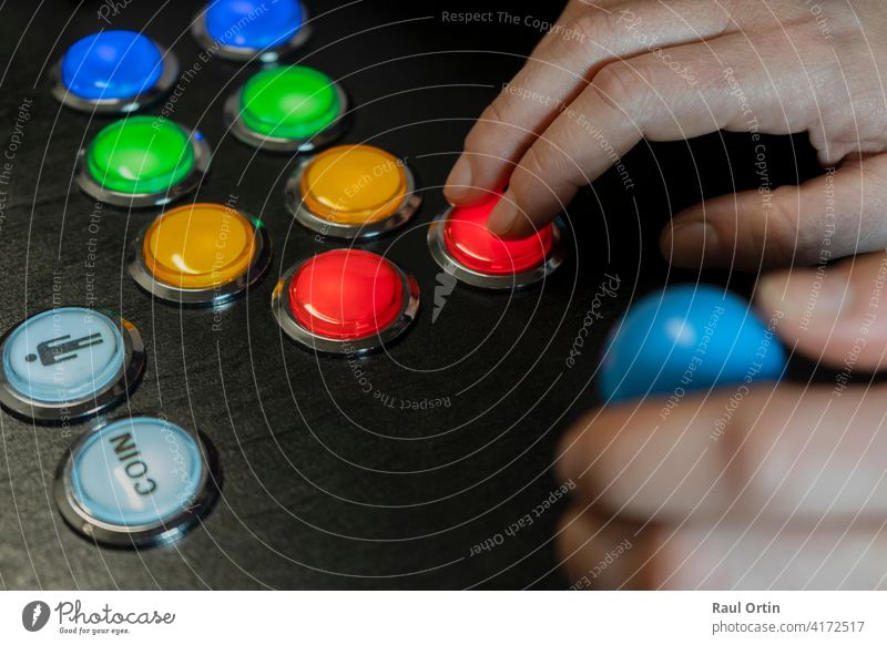 Closeup view of hands playing arcade old video games.Gamepad with joystick and many colorful buttons .Gaming with old retro technology concept lifestyle.