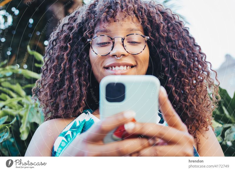 African girl's close-up using her smartphone female woman african hair face communication young technology black cellphone telephone joy smile mobile afro