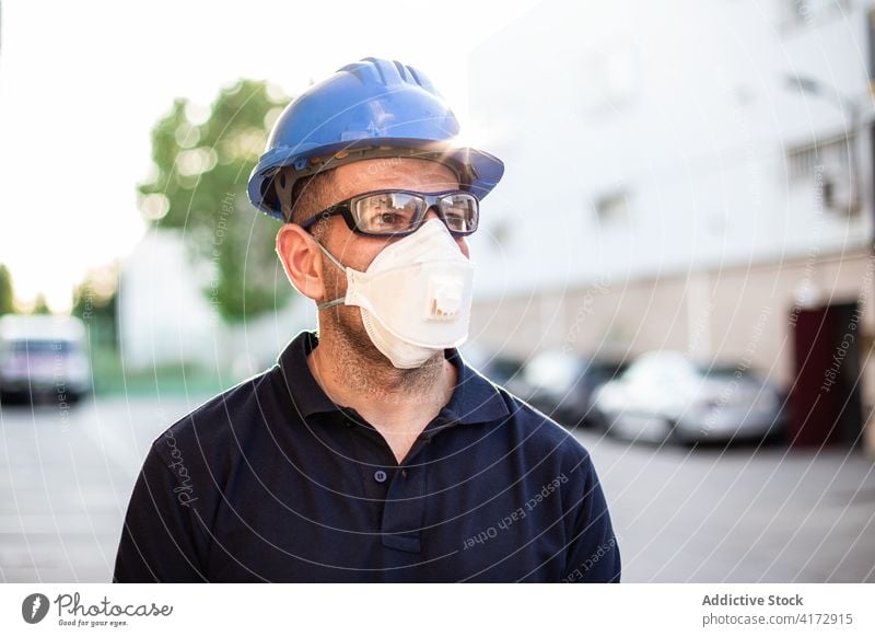 Workman in protective mask and glasses standing on street worker mechanic repairman respirator professional glove occupation male adult service lifestyle