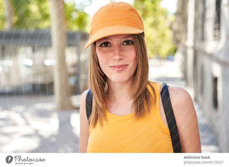 Teen girl with hat on city street urban teenage happy freckles positive female summer lifestyle young smile woman joy delight millennial student optimist orange