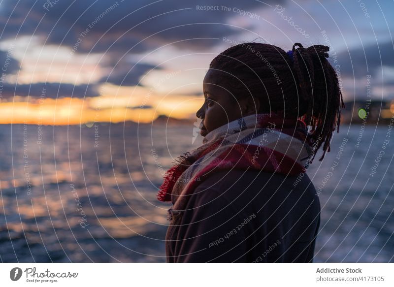 Black woman enjoying sunset over sea admire evening seascape tranquil warm clothes cold female ethnic black african american season outerwear seashore seaside