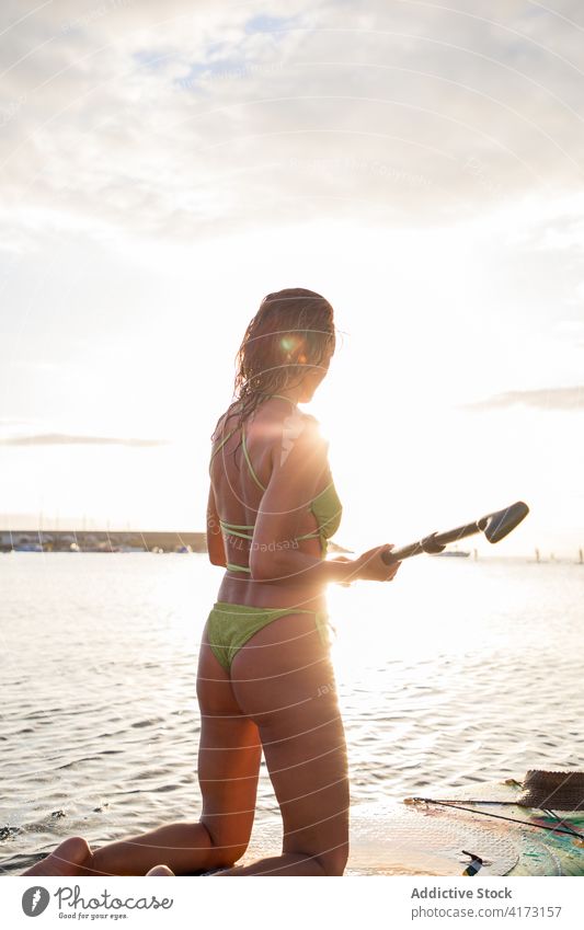 Fit woman standing on paddle board in sea water active slim surfer coast ocean beach female sup board paddleboard lifestyle summer shore recreation hobby nature