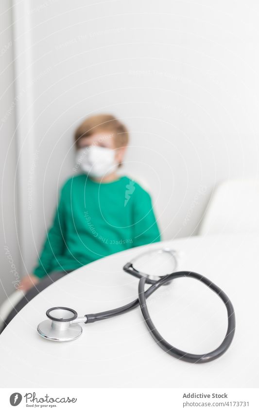 Unrecognizable kid in mask in hospital stethoscope phonendoscope medical room boy coronavirus covid 19 tool medicine office table epidemic covid19 clinic