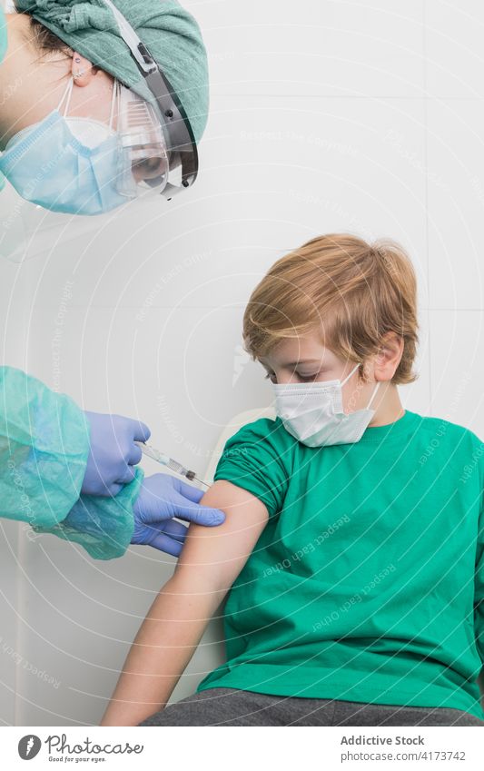 Doctor giving injection for kid in mask in hospital vaccine coronavirus syringe doctor child prevent covid 19 sterile health care medical professional