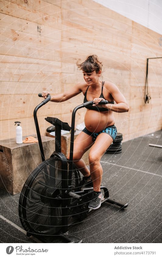 Pregnant woman doing exercises on air bike in sports center pregnant sportswoman gym cycle machine cardio functional training female athlete physical wellbeing