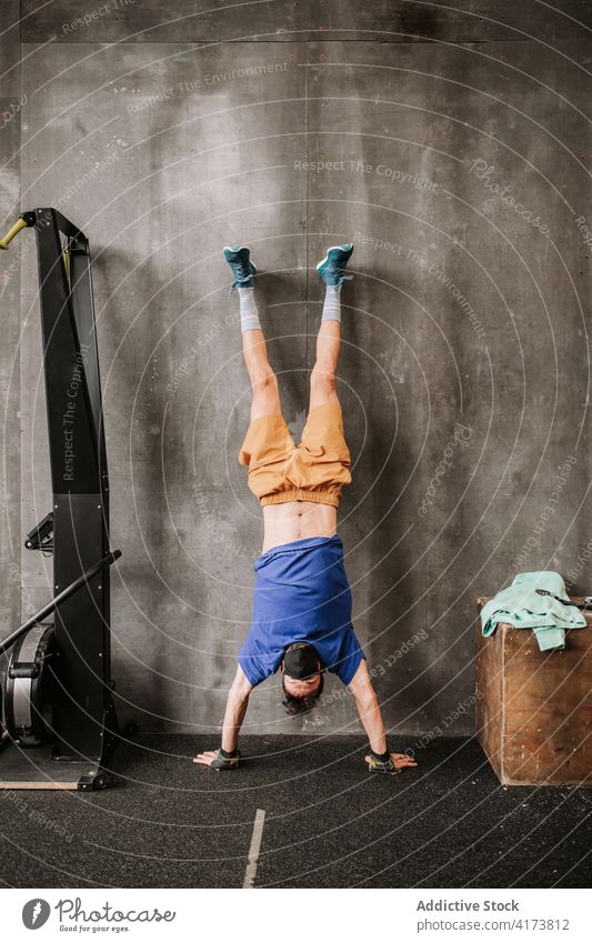 Sportsman in mask in handstand in gym sportsman wall training balance new normal workout strong male modern healthy effort power practice wellness strength
