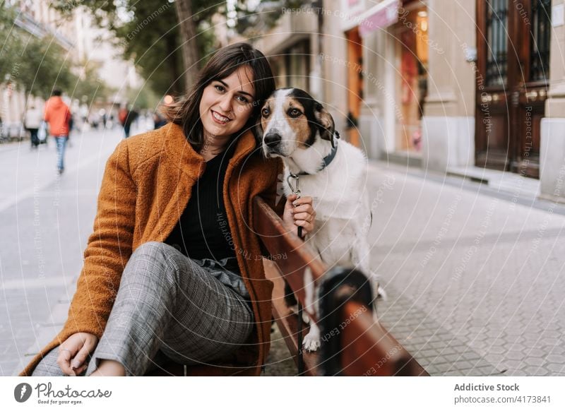 Smiling woman with adorable dog on street friendly city bench pet animal stroll cheerful female wooden happy smile canine sit domestic joy owner lady obedient
