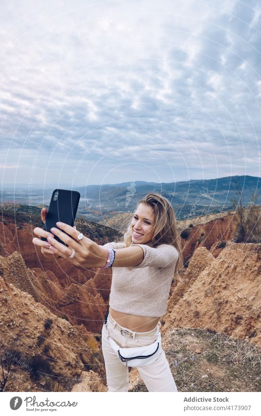 Happy traveler taking selfie in mountains woman nature rocky happy smartphone environment wild erosion landscape mobile gadget cheerful share sandstone