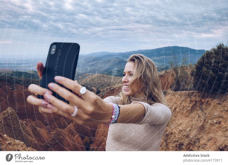 Happy traveler taking selfie in mountains woman nature rocky happy smartphone environment wild erosion landscape mobile female gadget cheerful sandstone