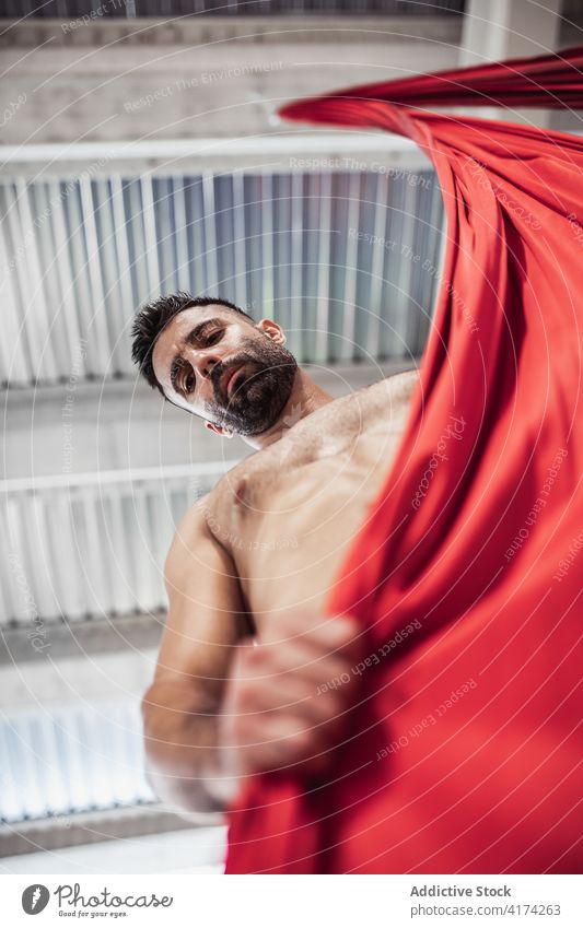Shirtless male dancer with red cloth man fabric grasp rehearsal studio silk shirtless gymnast practice adult ribbon ceiling choreography acrobatic perform art