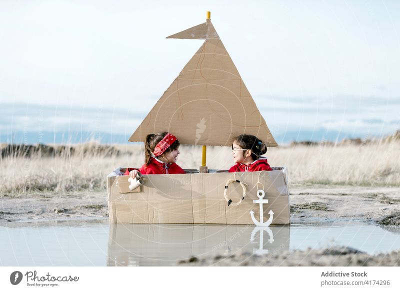 Curious kids playing in carton boat in countryside cardboard child together having fun spyglass inspiration game creative imagination girl handmade cheerful